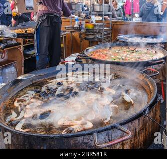 Große, dampfende Paella-Pfannen mit Garnelen und Muscheln, Hühnchen und Reis am Imbissstand am Portobello Road Market, Notting Hill, West London, England, Großbritannien. Stockfoto