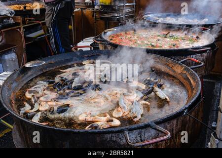 Große, dampfende Paella-Pfannen mit Garnelen und Muscheln, Hühnchen und Reis am Imbissstand am Portobello Road Market, Notting Hill, West London, England, Großbritannien. Stockfoto