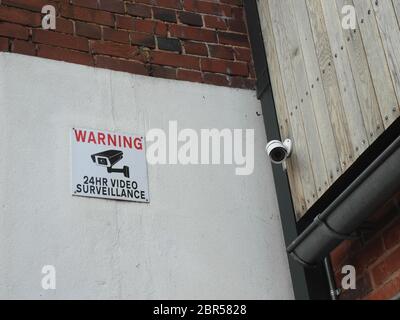 CCTV-Überwachungskamera und Warnschild für die Überwachung an den Außenwänden des Gebäudes Stockfoto