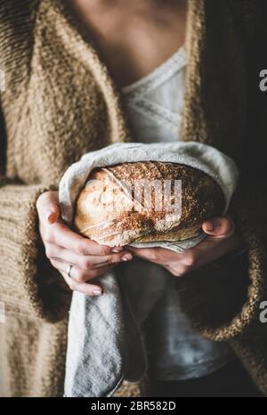 Junge Frau hält frisch gebackenen gesunden Weizen schwedischen Brot rund Brot in tpwel in den Händen, selektive Fokus Stockfoto