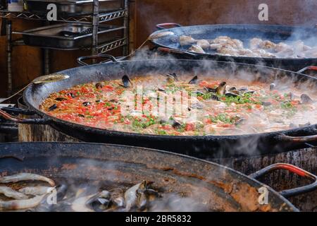 Große, dampfende Paella-Pfannen mit Garnelen und Muscheln, Hühnchen und Reis am Imbissstand am Portobello Road Market, Notting Hill, West London, England, Großbritannien. Stockfoto