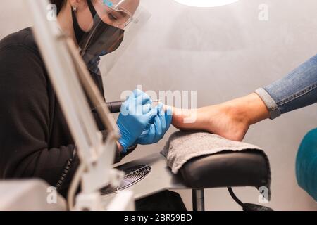 Pediküre Master poliert Nägel mit Nagel Feile Bohrer vor dem Auftragen Lack Seitenansicht Stockfoto