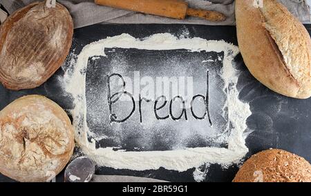 Inschrift Brot auf weißem Weizenmehl verstreut, in der Ecke liegen runde gebackenen Brote, Hintergrund für die Bäckerei Stockfoto