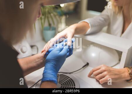 Manikurist schneidet die Nagelhaut auf den Nägel des Kunden mit einem Nipper Stockfoto