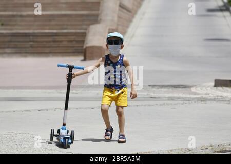 Ankara, Türkei. Mai 2020. Ein Junge mit einer Maske spielt am 20. Mai 2020 in Ankara, Türkei, mit seinem Roller. Die türkische Gesundheitsministerin Fahrettin Koca berichtete am Mittwoch über 972 neue COVID-19-Fälle und 23 weitere Todesfälle im Land. Kredit: Mustafa Kaya/Xinhua/Alamy Live News Stockfoto