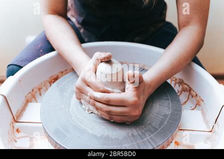 Prozess der Schaffung und Bildung einer weißen Tonkeramikplatte. Professionelle Töpfer ist in der Modellierung Tonplatten beschäftigt. Potter arbeitet in einer Werkstatt Stockfoto