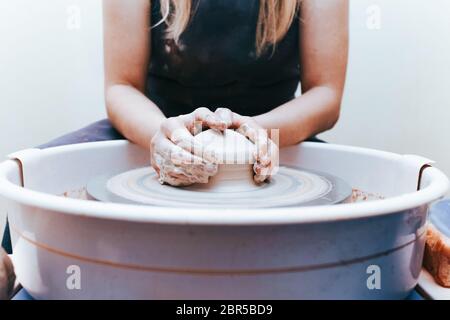 Prozess der Schaffung und Bildung einer weißen Tonkeramikplatte. Professionelle Töpfer ist in der Modellierung Tonplatten beschäftigt. Potter arbeitet in einer Werkstatt Stockfoto