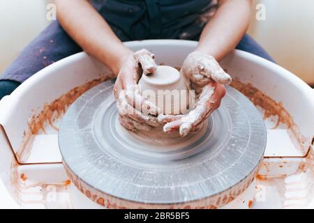 Prozess der Schaffung und Bildung einer weißen Tonkeramikplatte. Professionelle Töpfer ist in der Modellierung Tonplatten beschäftigt. Potter arbeitet in einer Werkstatt Stockfoto