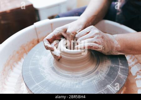 Prozess der Schaffung und Bildung einer weißen Tonkeramikplatte. Professionelle Töpfer ist in der Modellierung Tonplatten beschäftigt. Potter arbeitet in einer Werkstatt Stockfoto