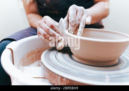 Prozess der Schaffung und Bildung einer weißen Tonkeramikplatte. Professionelle Töpfer ist in der Modellierung Tonplatten beschäftigt. Potter arbeitet in einer Werkstatt Stockfoto