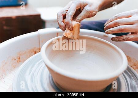 Prozess der Schaffung und Bildung einer weißen Tonkeramikplatte. Professionelle Töpfer ist in der Modellierung Tonplatten beschäftigt. Potter arbeitet in einer Werkstatt Stockfoto