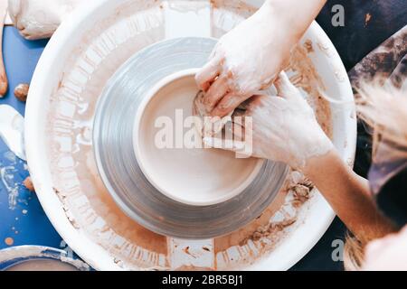 Prozess der Schaffung und Bildung einer weißen Tonkeramikplatte. Professionelle Töpfer ist in der Modellierung Tonplatten beschäftigt. Potter arbeitet in einer Werkstatt Stockfoto