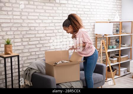 Glückliche Frau Öffnen der Paketbox zu Hause Stockfoto
