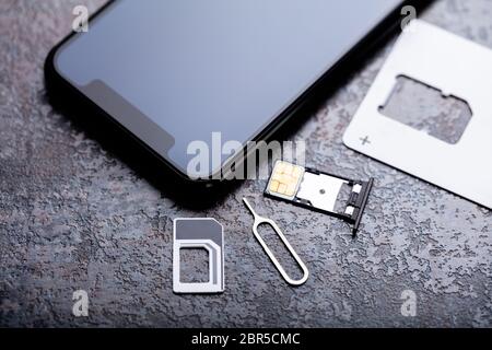 Handy in der Nähe von Nano-SIM-Karte in den Card Adapter mit Eject Pin über konkreten Hintergrund Stockfoto