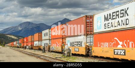 JASPER, ALBERTA, KANADA - JUNI 2018: Ein langer Güterzug mit Schiffscontainern, der durch Jasper, Kanada, fährt. Stockfoto