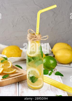Kaltes Getränk mit Zitronen, Minze, Limette in ein Glas Flasche und einen gelben cocktail Rohr, in der Nähe der Zutaten für die Herstellung von Stockfoto
