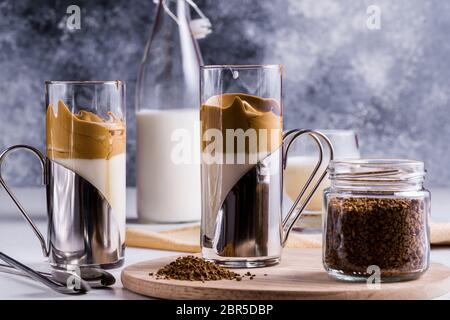 Dalgona Kaffee Espresso Latte mit einem kühlen flauschigen Schlagschaum in Gläsern auf grauem Hintergrund. Stockfoto