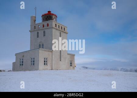 Panoramabild der Leuchtturm am Kap Dyrholaey mit Schnee und am frühen Morgen Licht, Winter in Island Stockfoto