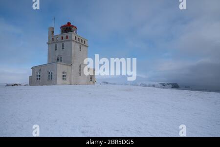 Panoramabild der Leuchtturm am Kap Dyrholaey mit Schnee und am frühen Morgen Licht, Winter in Island Stockfoto