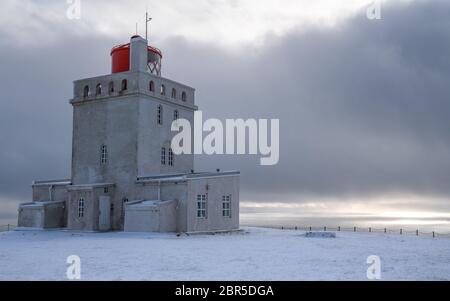 Panoramabild der Leuchtturm am Kap Dyrholaey mit Schnee und am frühen Morgen Licht, Winter in Island Stockfoto