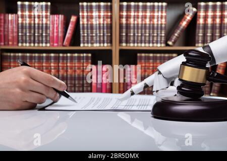 Roboterhand Unterstützung der Person, die für die Unterzeichnung dieses Dokuments reflektierende Schreibtisch Im Gerichtssaal Stockfoto