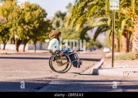 Junger Mann im Rollstuhl nähert sich der Bordsteinkante der Stadt Stockfoto