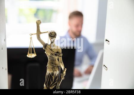 Gerechtigkeit Statue auf Regal und Anwalt Arbeiten im Büro im Hintergrund Stockfoto