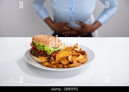 Junge Frau mit Magenschmerzen Beim Frühstück Stockfoto