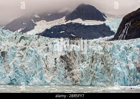 Der Überraschungsgletscher mit der mittleren Moräne und dem in Harriman Fjord in der Nähe von Whittier, Alaska schwimmenden Braseis. Surprise Glacier ist der aktivste kalbende Tauch-Gletscher im Prince William Sound. Stockfoto