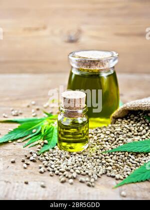 Hanf Öl in zwei Gläser mit Getreide im Sack, Blätter und Stängel von Cannabis auf dem Hintergrund der Holzbretter Stockfoto