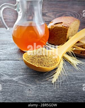 Malz in einem Löffel, Brot, kwass in einem Krug und ährchen auf dem Hintergrund der dunklen Holz- Board Stockfoto