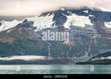 Schmelzwasser stürzt vom Serpentine Glacier in Barry Arm im Harriman Fjord, nahe Whittier, Alaska, auf den Mount Gilbert ab. Der Gletscher hat sich dramatisch von einem Leckerbisse zum hängenden Gletscher zurückgebildet. Stockfoto