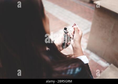 Frau füllt Flüssigkeit in E-Zigarette Nahaufnahme. Mädchen füllt Flüssigkeit in vape. Elektronisches Zigarettenkonzept Stockfoto