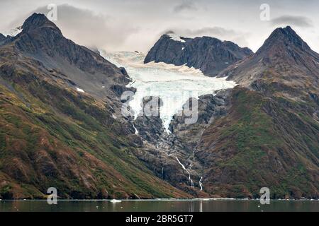 Schmelzwasser stürzt vom Serpentine Glacier in Barry Arm im Harriman Fjord, nahe Whittier, Alaska, auf den Mount Gilbert ab. Der Gletscher hat sich dramatisch von einem Leckerbisse zum hängenden Gletscher zurückgebildet. Stockfoto