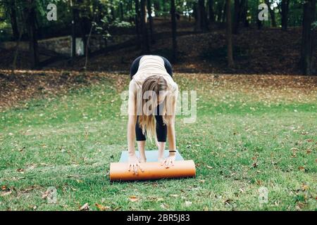 Junge schlanke Mädchen faltet ihren Teppich nach Yoga-Übung Stockfoto