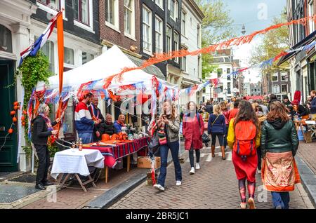 Amsterdam, Niederlande - 27. April 2019: Menschen kaufen und verkaufen auf dem traditionellen Flohmarkt während des Königstages, Koningsdag. Straßen mit holländischen Flaggen und Nationalfarben dekoriert. Stockfoto