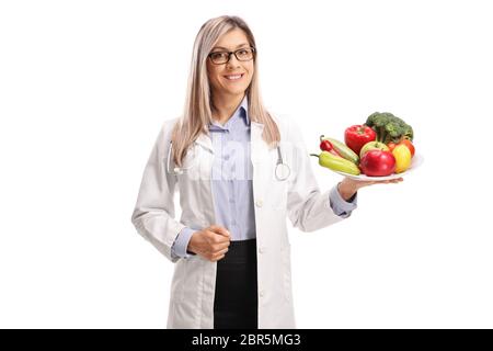 Ärztin hält einen Teller mit frischem Obst und Gemüse isoliert auf weißem Hintergrund Stockfoto