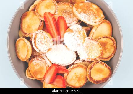 Nahaufnahme von Mini-Pfannkuchen Müsli mit Erdbeeren in blauer Schüssel zum Frühstück als neue trendige Aktivitäten beim Essen während der Quarantäne Coronavirus gesperrt, er Stockfoto