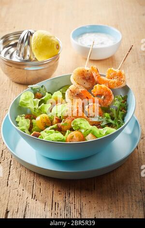 Gourmet Meeresfrüchte Starter von zart gegrillten würzigen Jakobsmuscheln und Garnelen auf Holzspieße in einen frischen grünen Salat mit Croutons serviert. Stockfoto