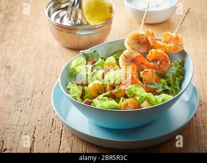 Gourmet Meeresfrüchte Vorspeise mit Garnelen und Jakobsmuscheln am Spieß gegrillt und serviert auf einem grünen Salat mit gebratenen Croutons in der Nähe zu hohen Winkel v Stockfoto