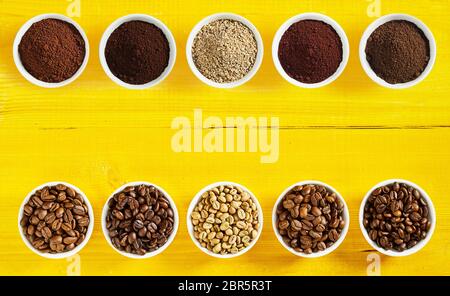 Mit einer Auswahl von verschiedenen Rohstoffen und Geröstete Kaffeebohnen und gemahlener Kaffee in getrennten Schüsseln arrangiert ordentlich von oben und unten mit zentralen Kopie s Stockfoto