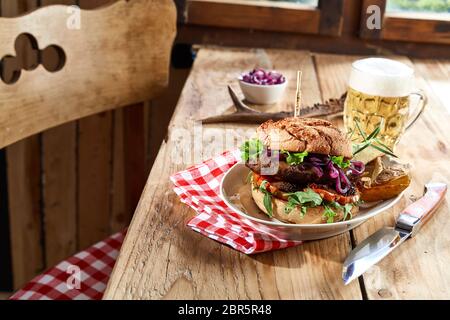 Spezialität wild Beef Burger auf ein knuspriges Brötchen mit schaumigem Bier und Kartoffel Kanten für eine rustikale Taverne Mittagessen Stockfoto