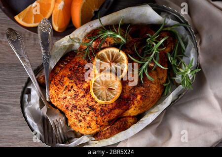 Gebackenes Hähnchen in Gewürzen mit knusprig appetitlich gebratener Kruste in einem Tablett, dunkel launisch Stockfoto