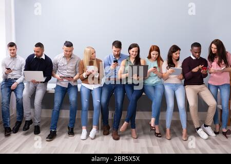 Multirassischen tausendjährigen Menschen in Zeile beschäftigt sich mit modernen elektronischen Gadgets Stockfoto