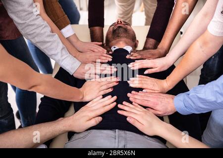 Gruppe der Hände berühren Körper liegen auf Tabelle während Reiki Sitzung Stockfoto