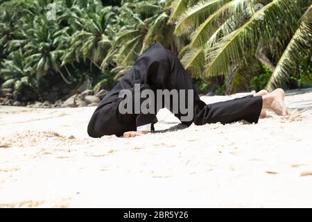 Seitenansicht der erfolglosen Geschäftsmann vergrub seinen Kopf in den Sand am Strand Stockfoto