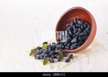 Geißblatt Beeren in einer Keramikschale auf Holzhintergrund. Stockfoto