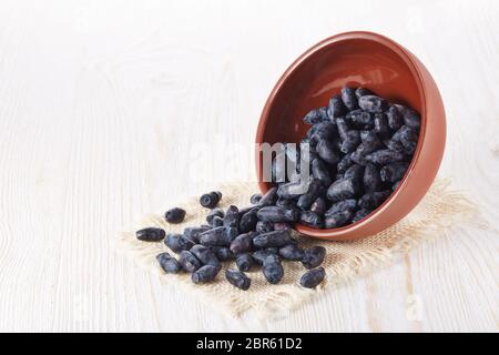 Geißblatt Beeren in einer Keramikschale auf Holzhintergrund. Stockfoto