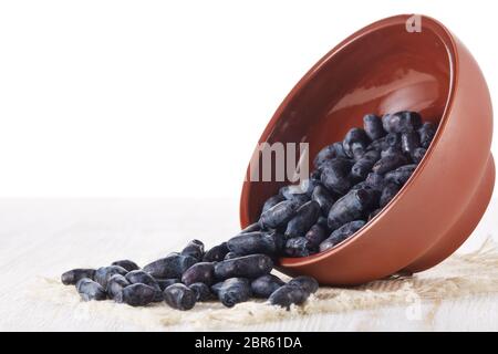 Geißblatt Beeren in einer Keramikschale auf einem Holztisch auf weißem Hintergrund. Stockfoto