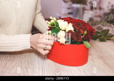 Blumenladen Floristin Herstellung Box mit roten Rosen. Prozess der Erstellung Hut-Box mit Blumen Stockfoto
